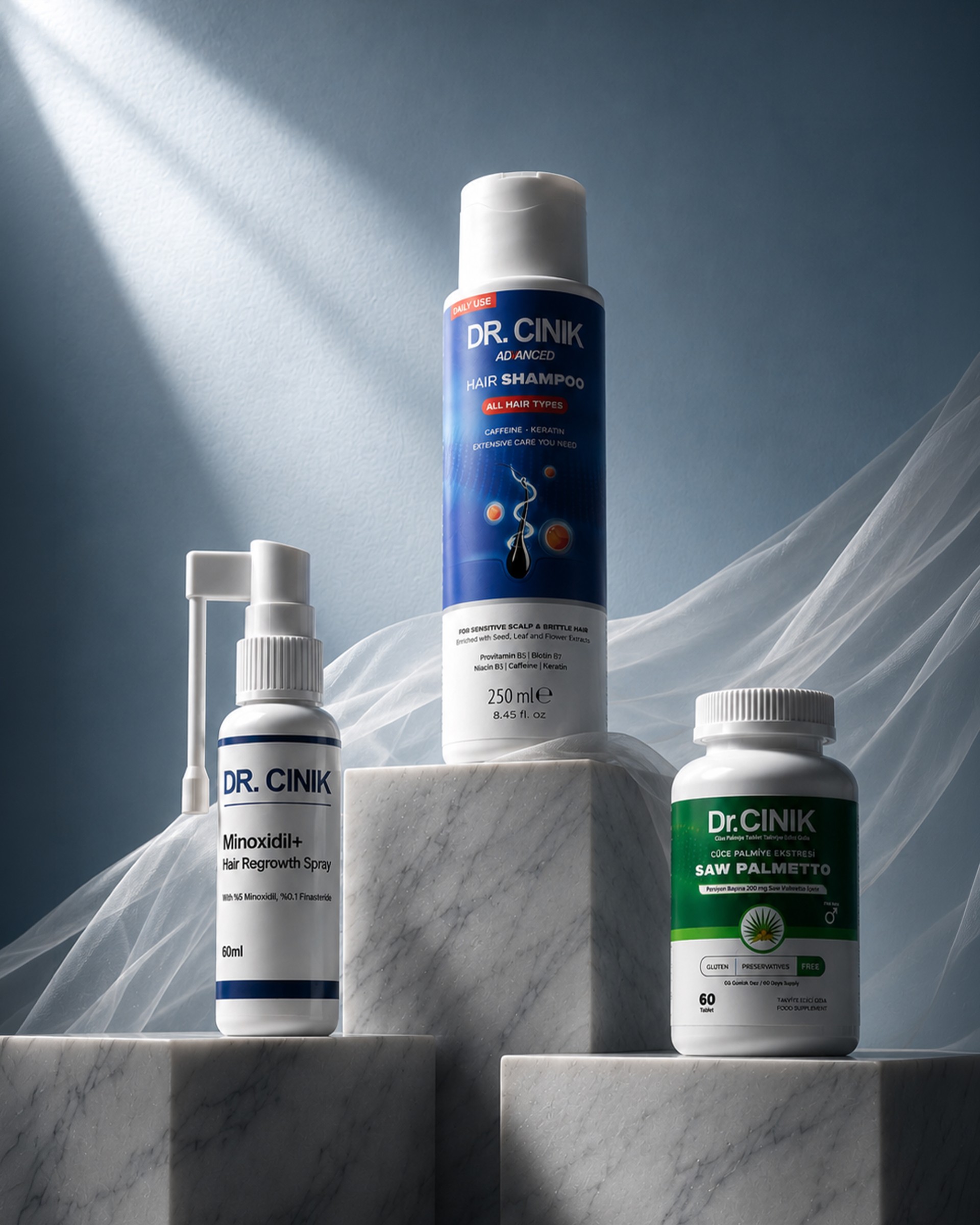 Dr. Cinik Minoxidil+ hair regrowth spray, Advanced hair shampoo and Saw Palmetto food supplement arranged on marble plinths.